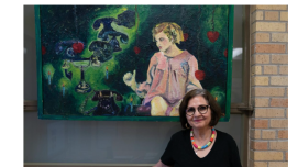 News Article screenshot of Maggie Rivas-Rodriguez, in a black shirt, posing in front of artwork.