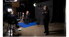 Maggie Rivas-Rodriguez standing in front of an oral history taking place.