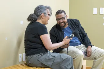 Two summer institute participants sitting down on a bench interviewing each other with a Zoom audio recorder.